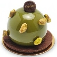 An Olive green round cake with pistachios on its surface